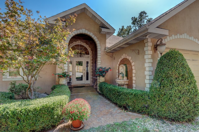 property entrance with a garage, french doors, and stucco siding