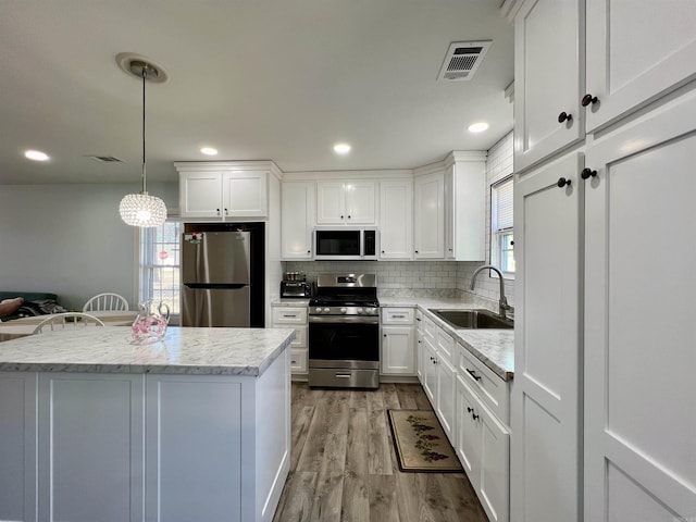 kitchen with visible vents, light wood-style flooring, decorative backsplash, appliances with stainless steel finishes, and a sink