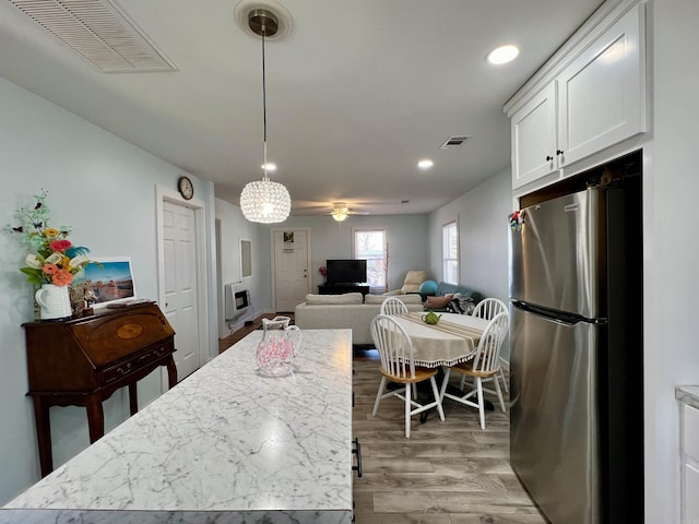 kitchen featuring visible vents, light wood finished floors, freestanding refrigerator, and white cabinetry