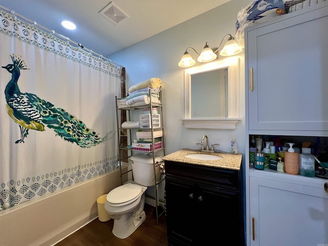 full bath featuring visible vents, toilet, wood finished floors, shower / bath combo with shower curtain, and vanity