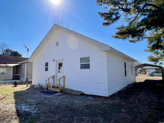 back of house with a carport, entry steps, and fence