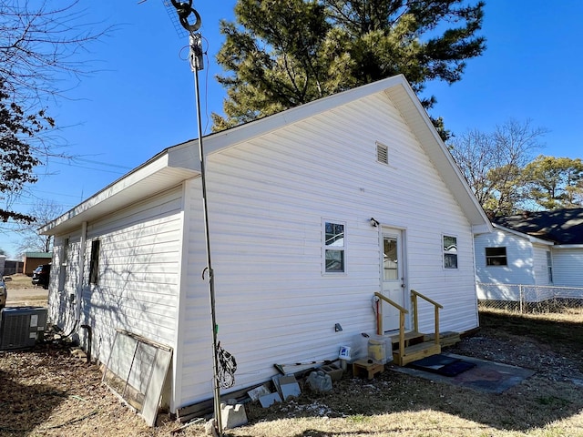 rear view of property featuring entry steps, central AC, and fence