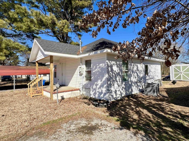 view of home's exterior featuring central AC unit, roof with shingles, and an outdoor structure