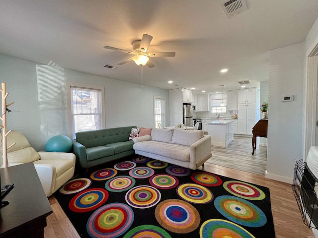 living room with visible vents, light wood-style flooring, and a wealth of natural light