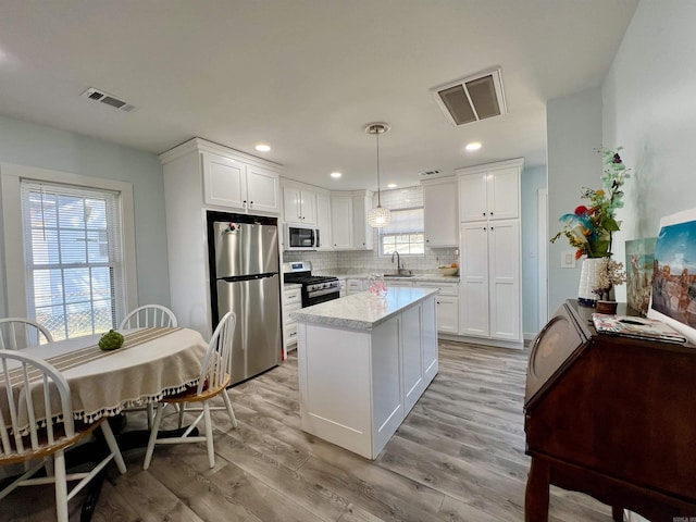 kitchen with light wood finished floors, visible vents, stainless steel appliances, light countertops, and a sink