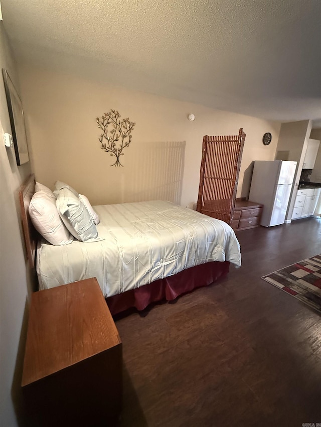 bedroom featuring freestanding refrigerator, a textured ceiling, and wood finished floors