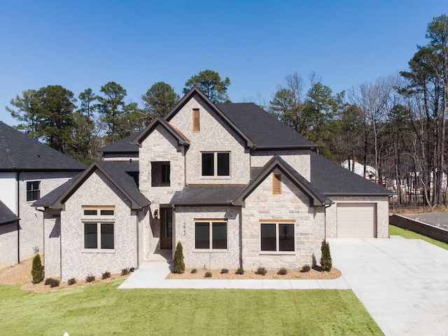 french country home featuring a garage, a shingled roof, driveway, stone siding, and a front yard