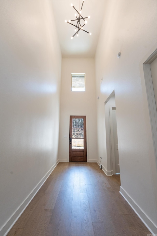 entrance foyer featuring a chandelier, a towering ceiling, baseboards, and wood finished floors