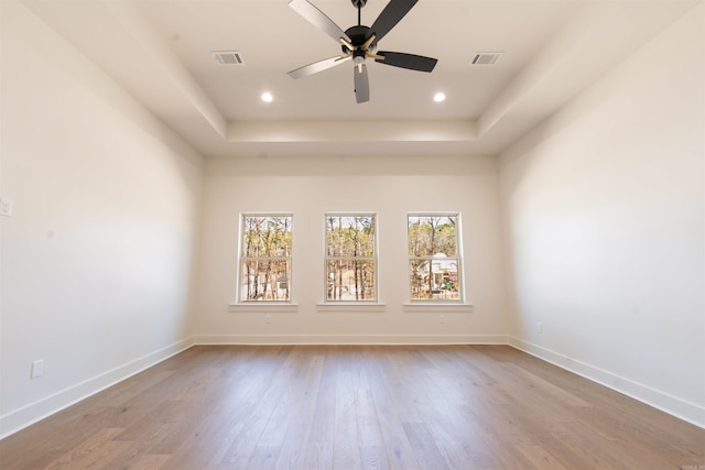 unfurnished room featuring baseboards, visible vents, and wood finished floors