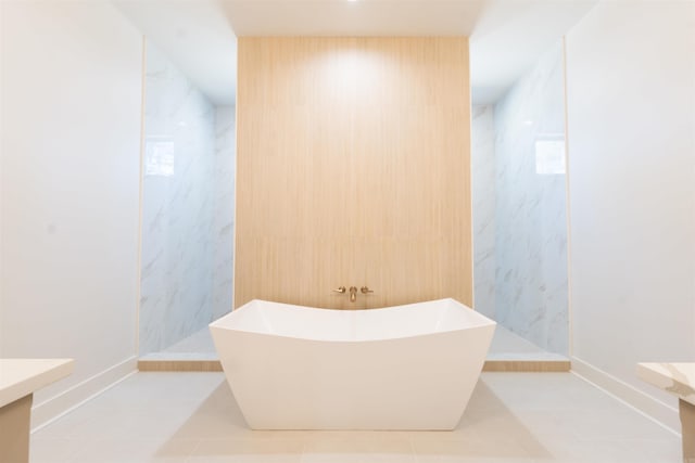 full bathroom featuring a marble finish shower, vanity, a freestanding tub, baseboards, and tile patterned floors