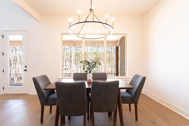 dining area featuring baseboards, wood finished floors, and an inviting chandelier