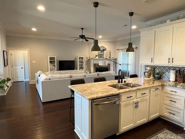 kitchen with a peninsula, a sink, white cabinetry, dishwasher, and crown molding