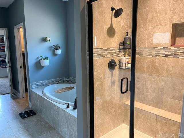 full bathroom featuring tile patterned flooring, a shower stall, and a bath