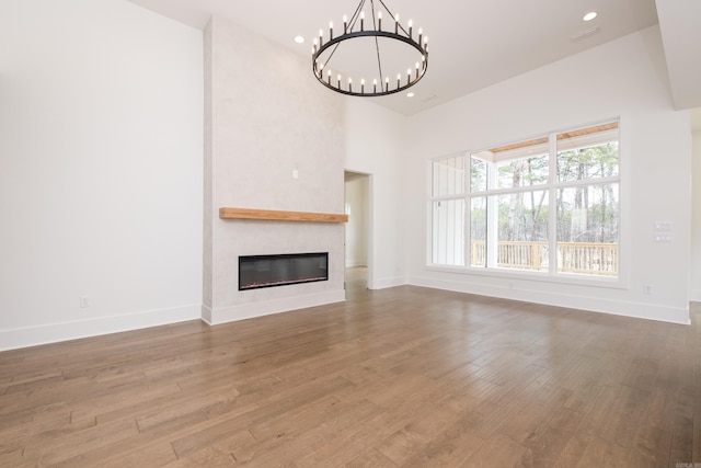 unfurnished living room with a chandelier, a fireplace, wood finished floors, and baseboards