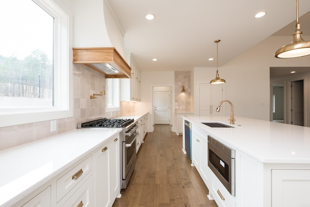 kitchen featuring stainless steel appliances, custom range hood, backsplash, white cabinetry, and a sink