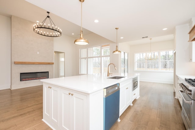 kitchen featuring appliances with stainless steel finishes, light wood-style floors, white cabinets, and a sink