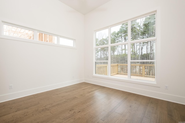 unfurnished room featuring baseboards and dark wood-style flooring