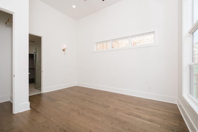 unfurnished bedroom featuring recessed lighting, wood finished floors, connected bathroom, and baseboards