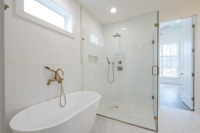 full bath with marble finish floor, tile walls, a freestanding bath, wainscoting, and tiled shower