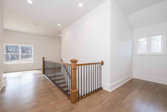 hall with recessed lighting, baseboards, wood finished floors, and an upstairs landing