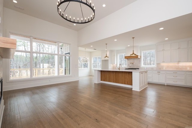 kitchen featuring dark wood-style floors, decorative backsplash, white cabinets, and a notable chandelier