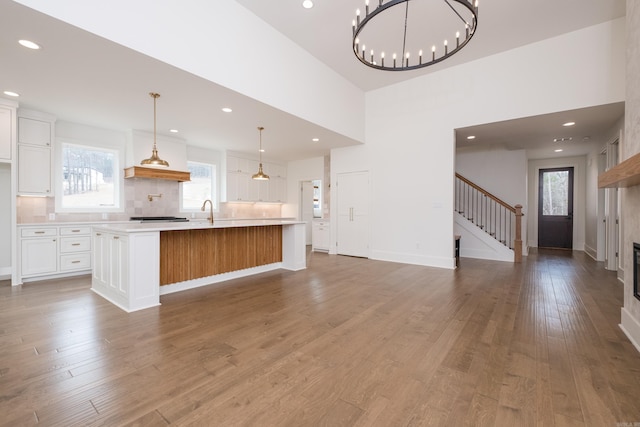 kitchen with white cabinets, a spacious island, wood finished floors, light countertops, and backsplash