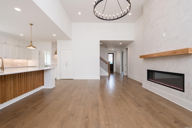 unfurnished living room with baseboards, a glass covered fireplace, light wood-style flooring, and recessed lighting