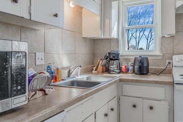 kitchen with white range with electric stovetop, a sink, light countertops, white cabinetry, and backsplash