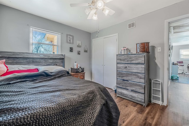 bedroom with ceiling fan, a closet, visible vents, and wood finished floors