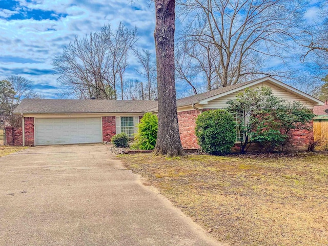 ranch-style house with concrete driveway, brick siding, and an attached garage