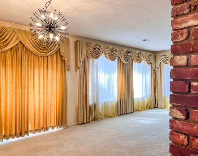 unfurnished living room featuring a textured ceiling, carpet flooring, visible vents, and an inviting chandelier