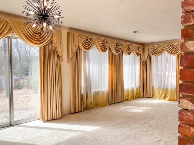 carpeted empty room with a chandelier, a textured ceiling, and visible vents