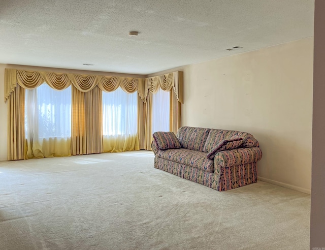 carpeted living room featuring baseboards, visible vents, and a textured ceiling