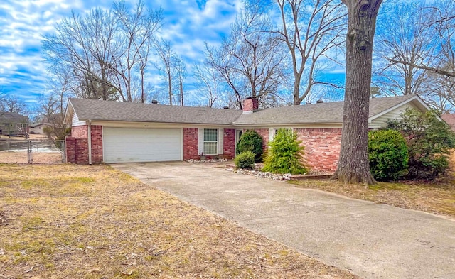 single story home featuring driveway, a chimney, an attached garage, fence, and brick siding