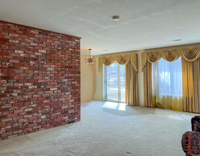 carpeted empty room featuring an inviting chandelier, visible vents, and a textured ceiling