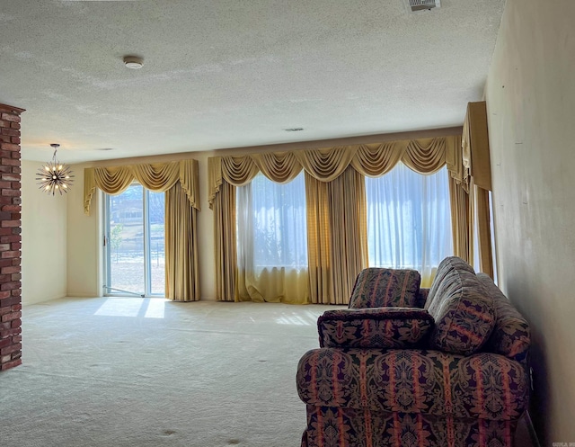 sitting room with carpet floors, a chandelier, and a textured ceiling