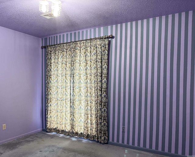 unfurnished room with a textured ceiling, visible vents, and baseboards