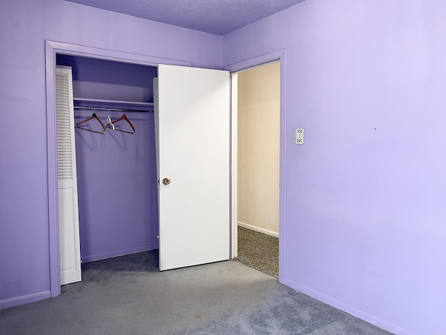 unfurnished bedroom with a textured ceiling, a closet, carpet, and baseboards