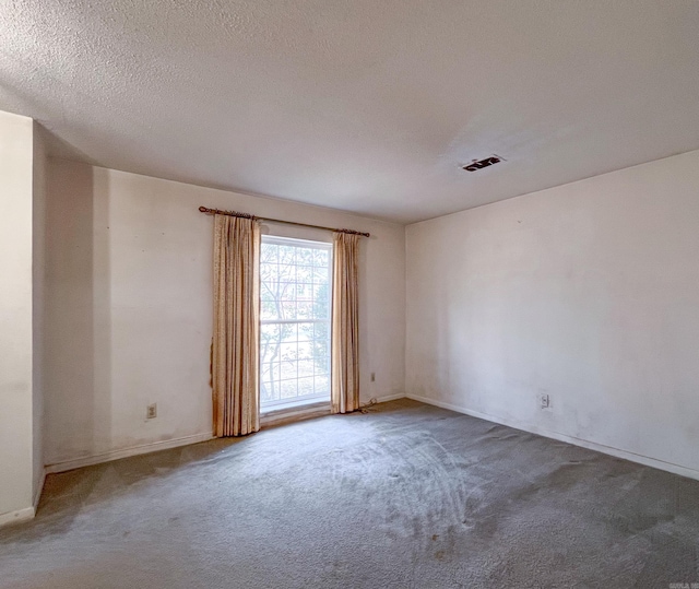 carpeted empty room with visible vents and a textured ceiling