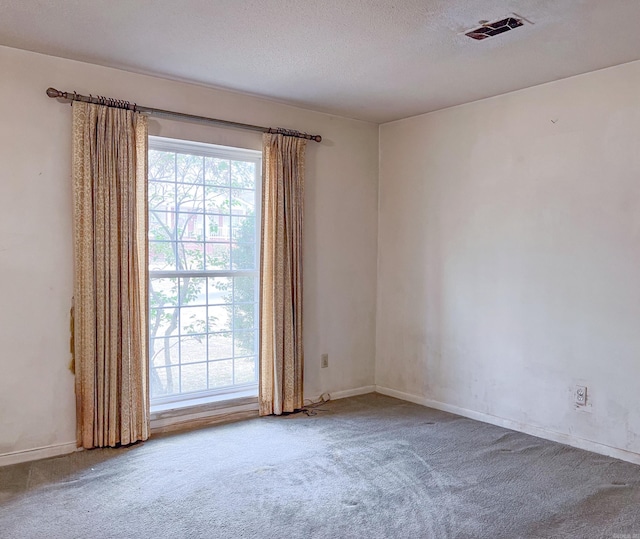 carpeted empty room with baseboards, visible vents, and a textured ceiling