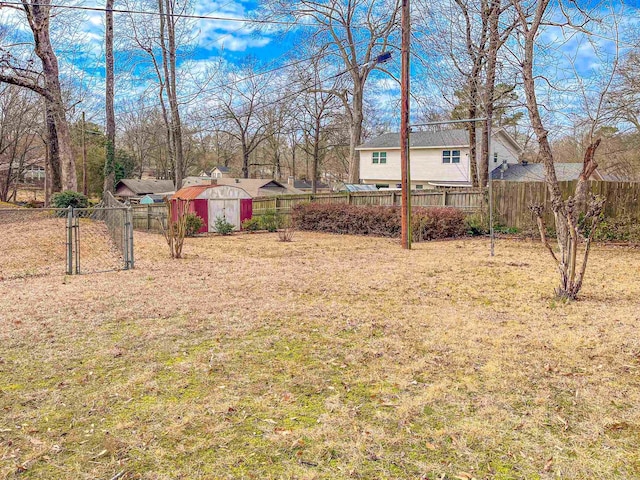 view of yard featuring a storage shed, an outdoor structure, fence, and a gate