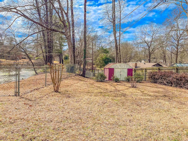 view of yard featuring an outbuilding, a storage unit, and fence private yard