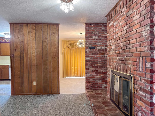 hall featuring a textured ceiling, dark colored carpet, wooden walls, and a notable chandelier