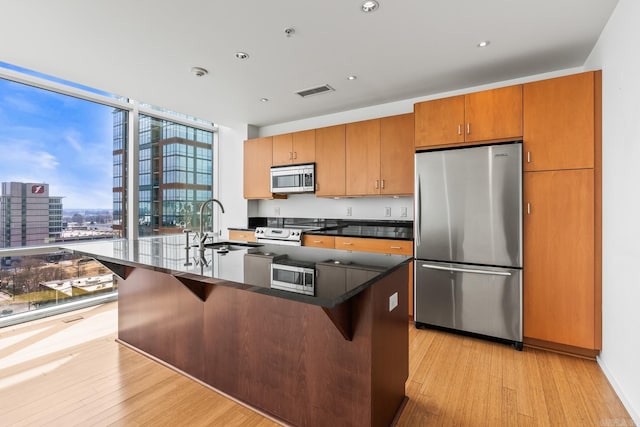 kitchen featuring light wood-type flooring, visible vents, appliances with stainless steel finishes, and a sink