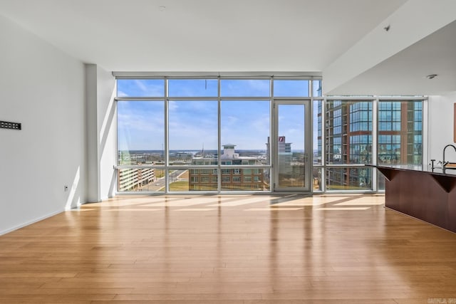 unfurnished living room featuring a view of city, plenty of natural light, wood finished floors, and floor to ceiling windows