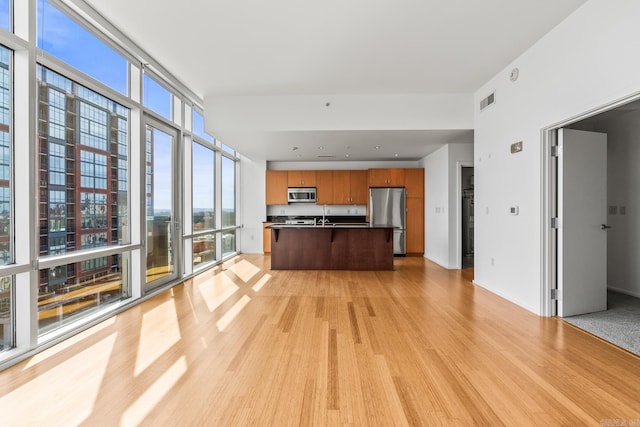 interior space with light wood-style floors, visible vents, baseboards, and a wall of windows