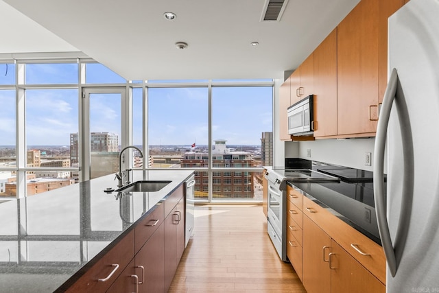 kitchen featuring a sink, visible vents, appliances with stainless steel finishes, floor to ceiling windows, and a view of city