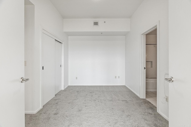 unfurnished bedroom with carpet, a closet, visible vents, ensuite bath, and baseboards