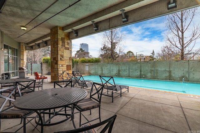 community pool featuring a patio, grilling area, and fence