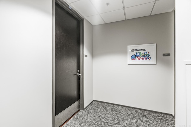 hallway with baseboards, a drop ceiling, and carpet flooring